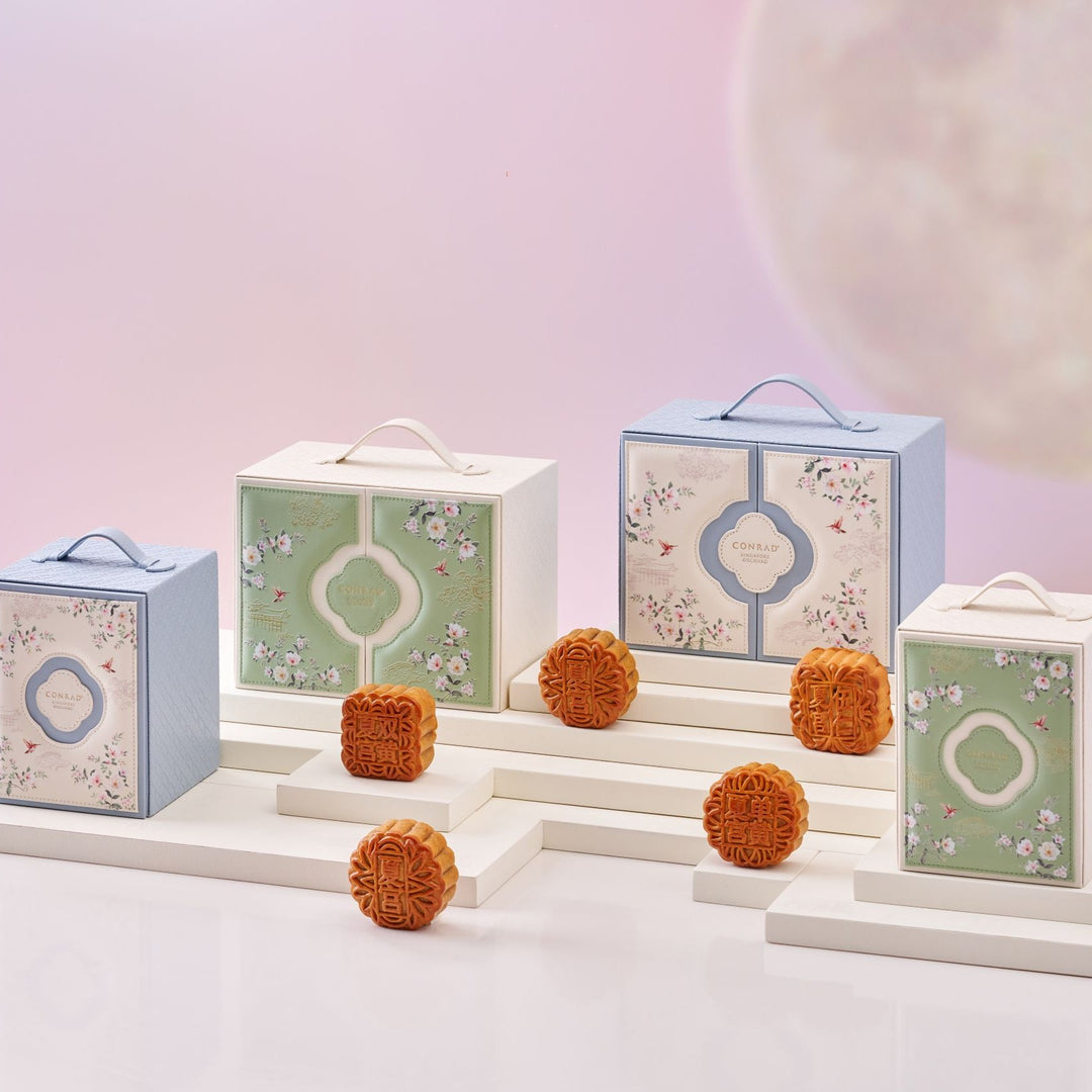 Decorative boxes with floral designs and mooncakes on a light background