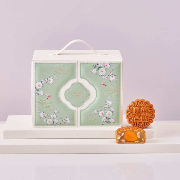 Gift box with floral design and two mooncakes on a light gray background